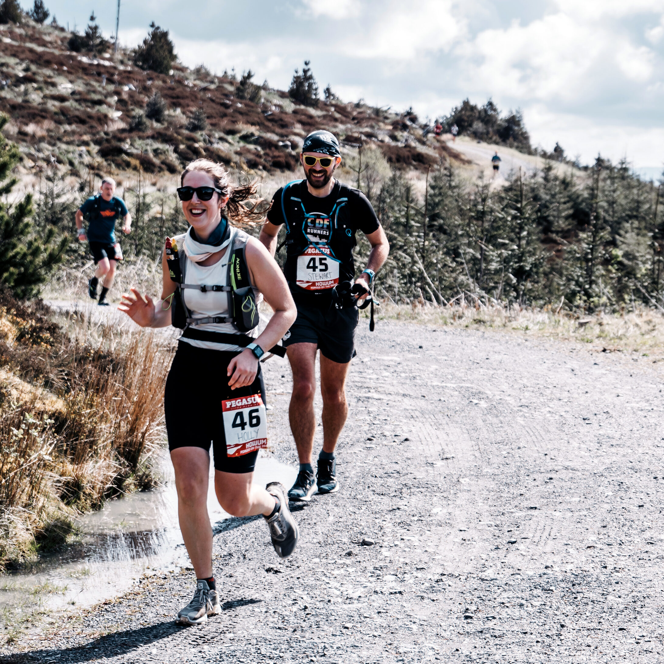 Holly and Stewart running on a gravel path and both smiling, probably because it's slightly downhill.