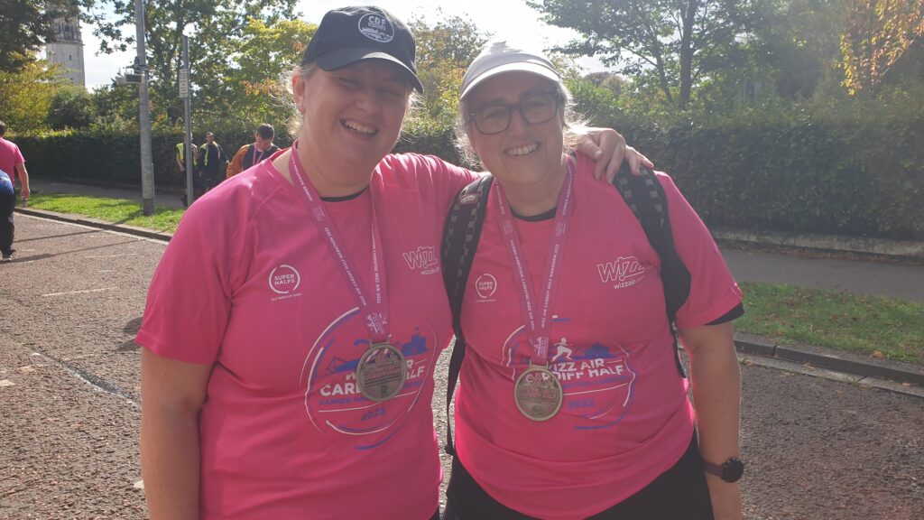 Charlotte and Ruth in ludicrously pink Cardiff half tshirts and medal arm in arm looking very proud.