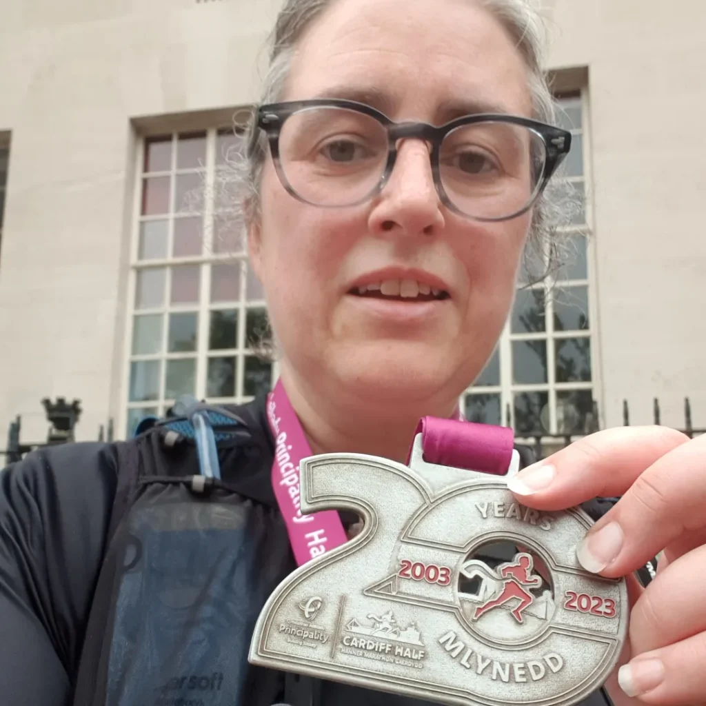 A selfie from Charlotte holding up a chonky Cardiff half medal from 2023. She looks knackered, but in a good way. 